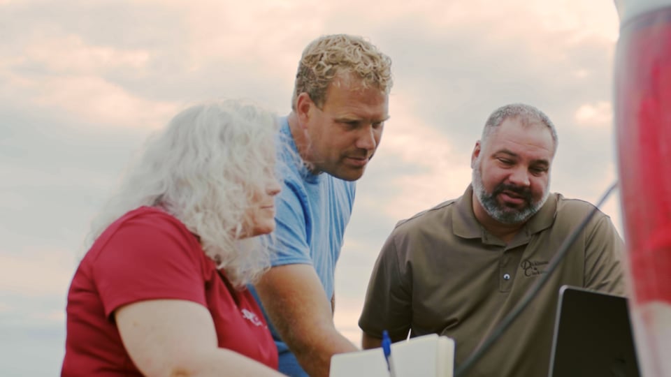 An adviser and two farmers looking at a laptop together