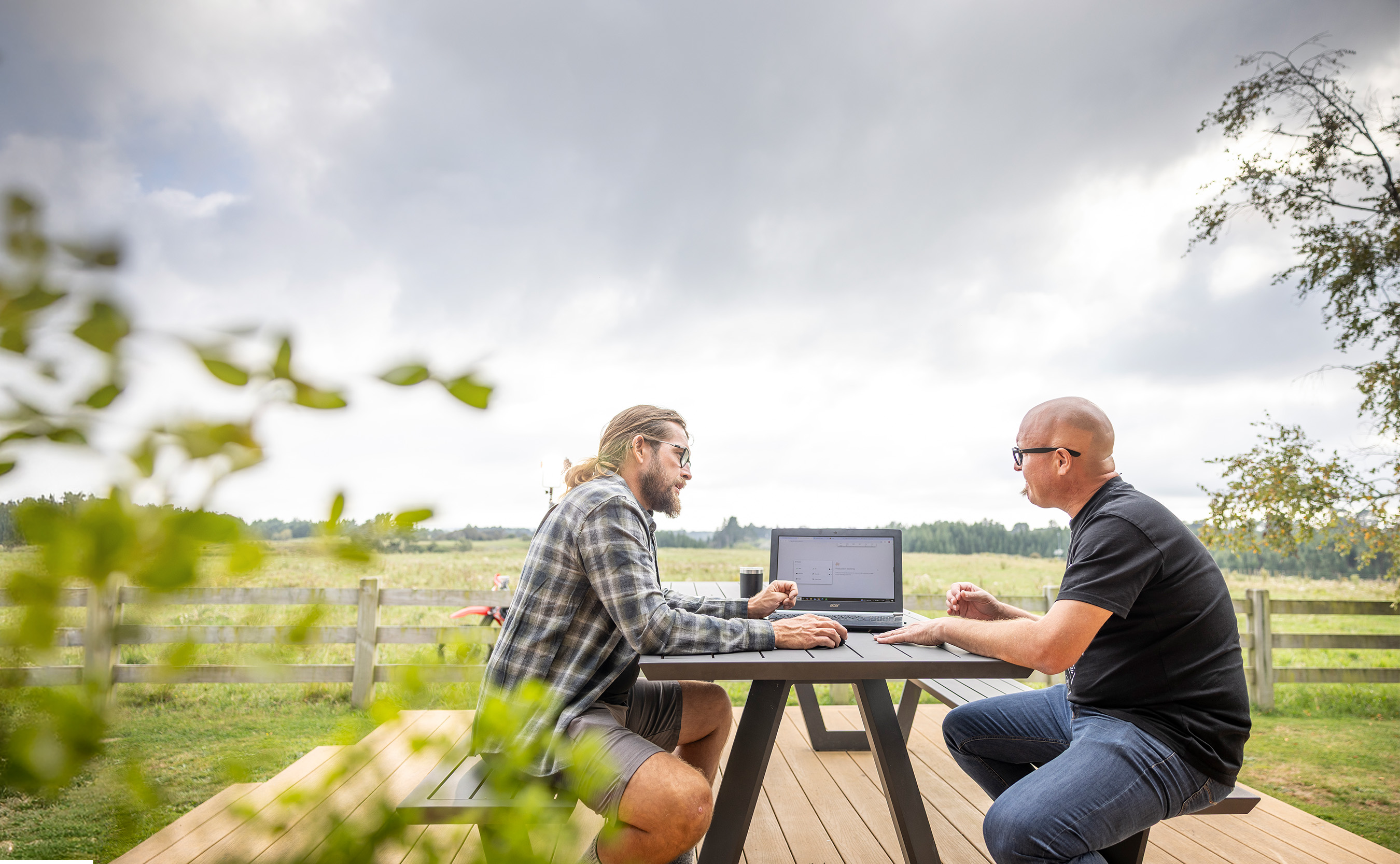 A farmer and his adviser working through figures on a laptop at an outdoor table