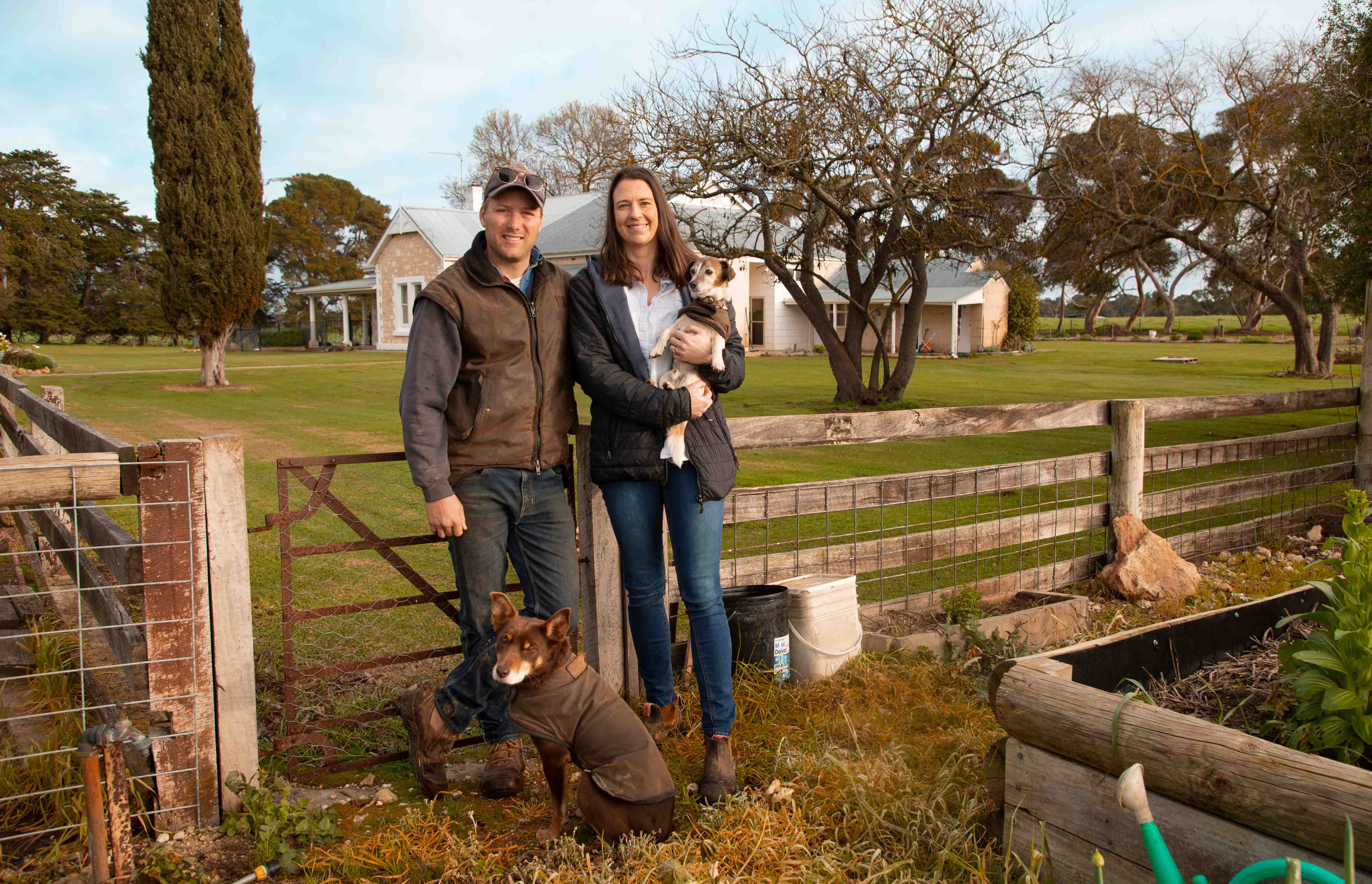 A farming couple and their dogs in front of the homestead